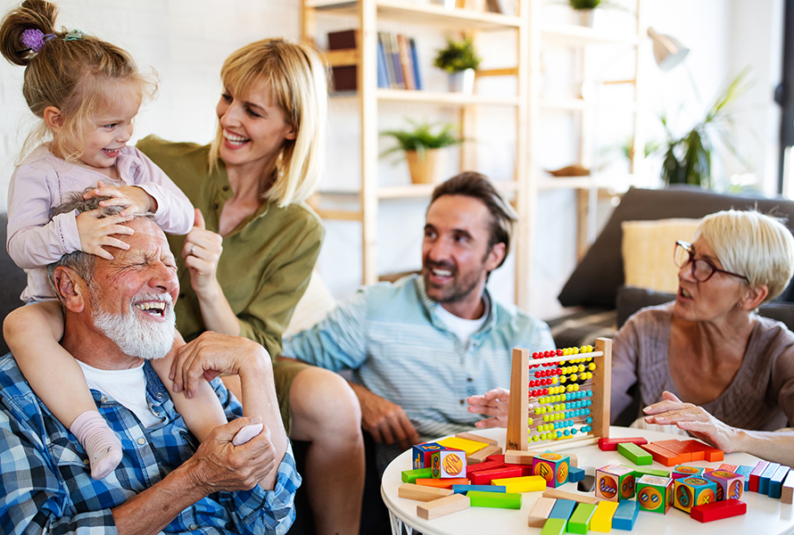 Fünf Personen, darunter ein Kind, beim Spielen im Wohnzimmer – ein Moment gelebter Familiengemeinschaft.