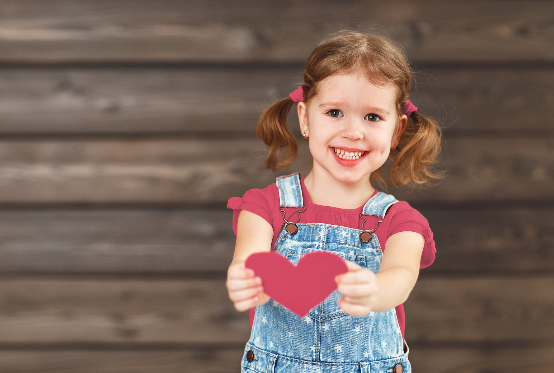 Une fillette tend un cœur vers la caméra – un symbole fort d’amour, de soin et d’humanité.