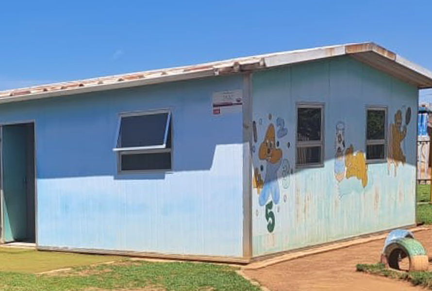 Das hellblau gestrichene KITA-Gebäude strahlt im Sonnenlicht – ein Symbol für Hoffnung, Bildung und den nachhaltigen Einsatz der Gemeinschaft.