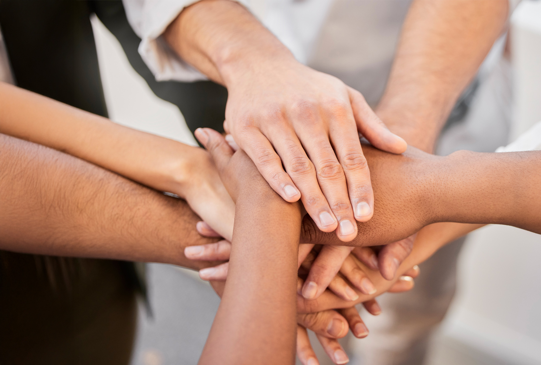 Diventare socio Un gruppo di persone sta in cerchio e sovrappone le mani al centro – un forte segno di comunità, fiducia e solidarietà.