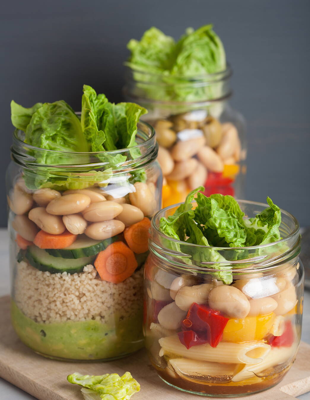 Salat im Glas – bunt, praktisch, gesund Drei Gläser gefüllt mit geschichtetem Salat aus Couscous, Pasta, Gemüse, Bohnen, Oliven und Blattsalat – ideal für unterwegs oder als Vorrat.