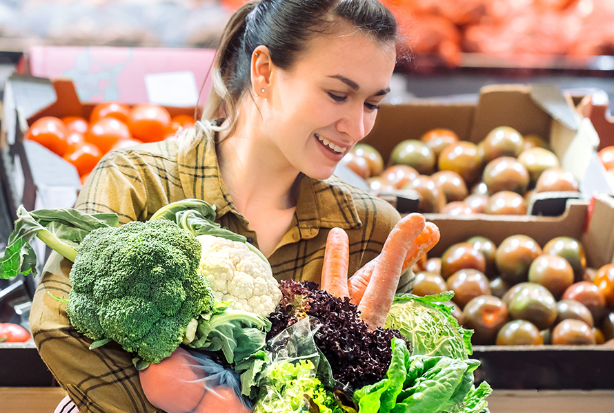 Frau kauft frisches Gemüse ein Eine Frau wählt frisches Gemüse wie Broccoli, Blumenkohl und Rüebli – Grundlage für eine ausgewogene Ernährung in der Schwangerschaft.