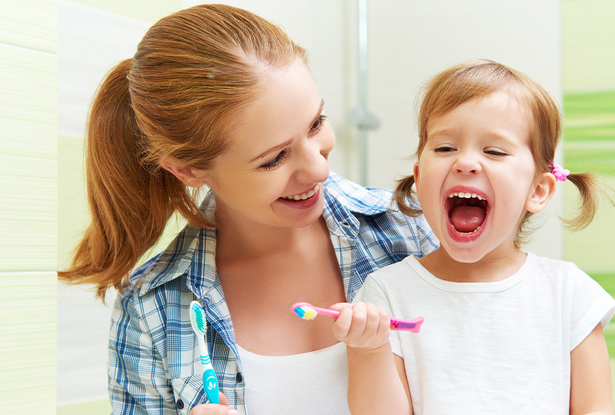 Mutter und Tochter beim Zähneputzen Liebevolle Szene, in der eine Mutter ihrer kleinen Tochter beim Zähneputzen unterstützt – ein wichtiger Schritt für gesunde Zähne und Vorsorge.
