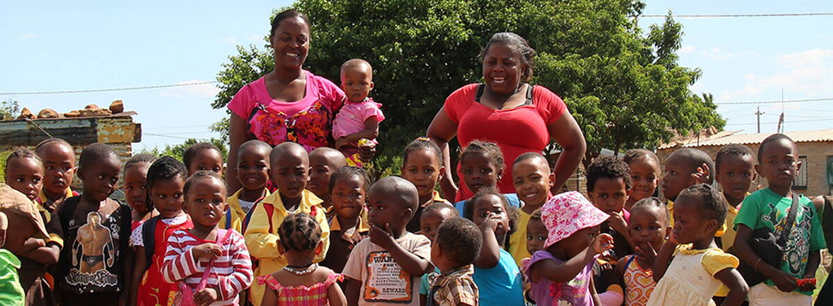 Kita Nkululeko – Südafrika Kinder der Kita Nkululeko lachen gemeinsam mit zwei Betreuerinnen – ein Ort voller Wärme, Bildung und Hoffnung mitten in Orange Farm.