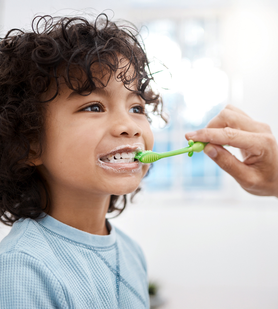 Lavarsi i denti con amore Un bambino si fa lavare i denti dalla madre – un momento che dimostra l’importanza della cura e della salute dentale fin da piccoli.