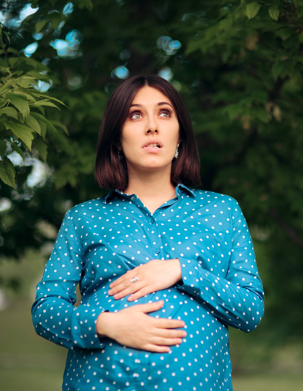 Donna con paura del parto – comprendere la tocofobia Una donna si tiene il ventre e appare infelice. L’immagine simboleggia la paura e il disagio causati dalla tocofobia, la paura patologica del parto.