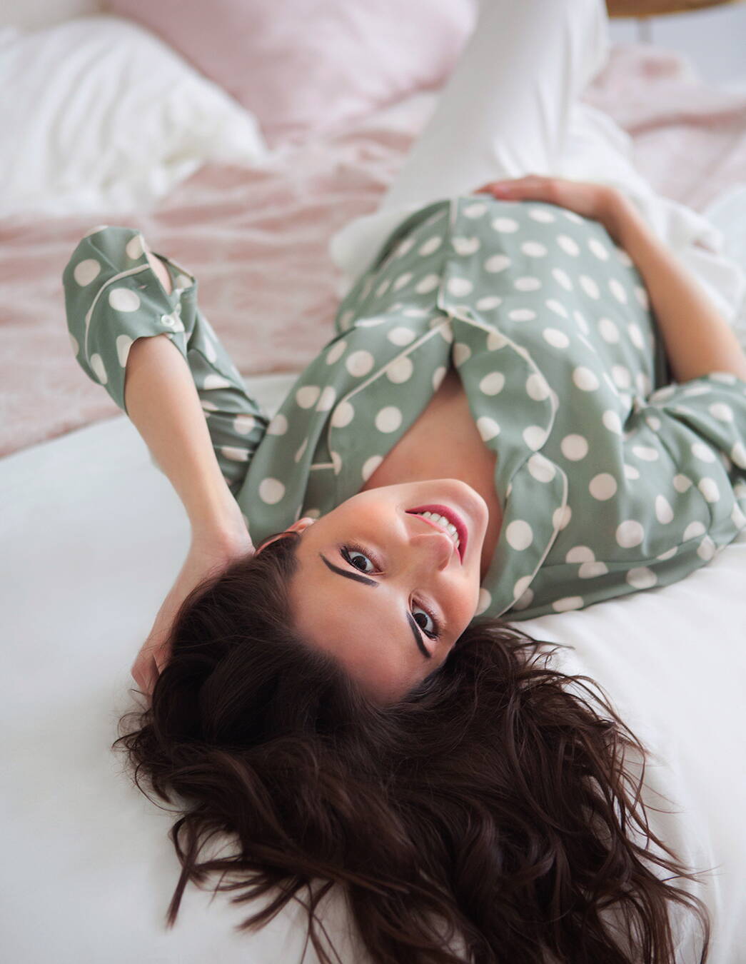 Strahlende Schwangere liegt entspannt auf dem Rücken und lächelt in die Kamera – eine Einladung, sich bewusst Ruhe zu gönnen.