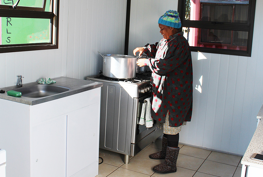 In der neuen Küche bereitet Gladys mit viel Liebe eine warme Mahlzeit für die Kinder zu – ein sichtbares Zeichen des Fortschritts in Nkululeko.