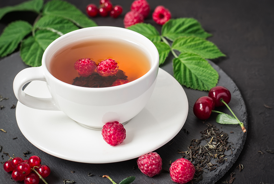 Himbeerblättertee: Pause in Woche 36 Eine Tasse Himbeerblättertee mit frischen und getrockneten Himbeerblättern – beliebt zur Geburtsvorbereitung, aber in dieser Woche ist eine kurze Einnahmepause empfohlen.
