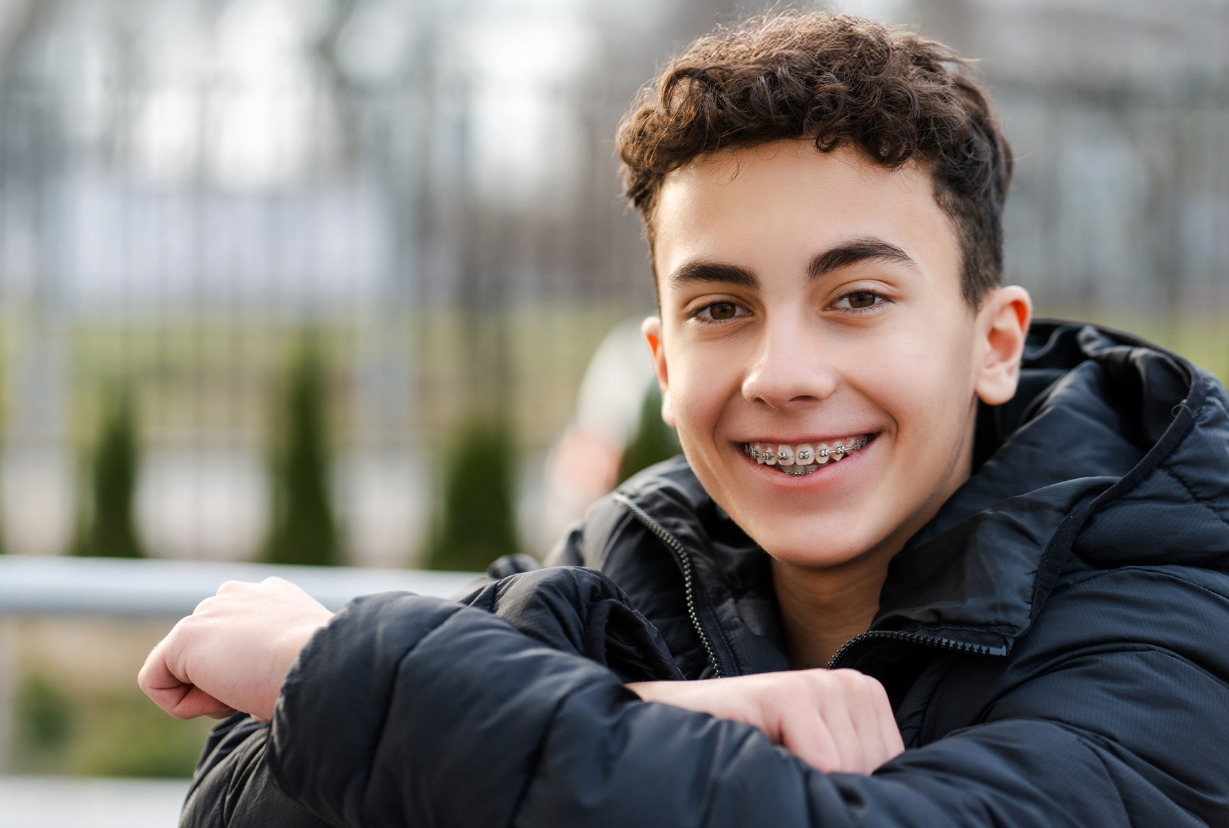 Lachen mit Zahnspange Ein Jugendlicher mit Zahnspange lacht in die Kamera – mit PRO LIFE kein Grund zur Sorge, denn Kieferorthopädie wird umfassend unterstützt.