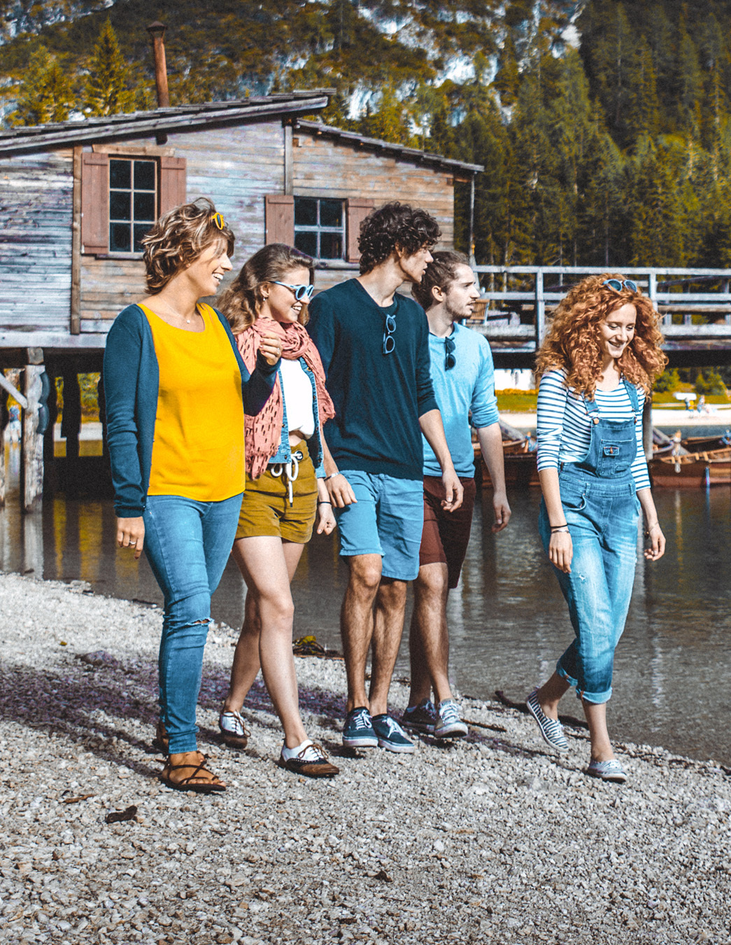 Cinque giovani passeggiano lungo la riva del lago – un momento di leggerezza che mostra cosa significa il tempo libero con MiBon: comunità, natura e gioia.