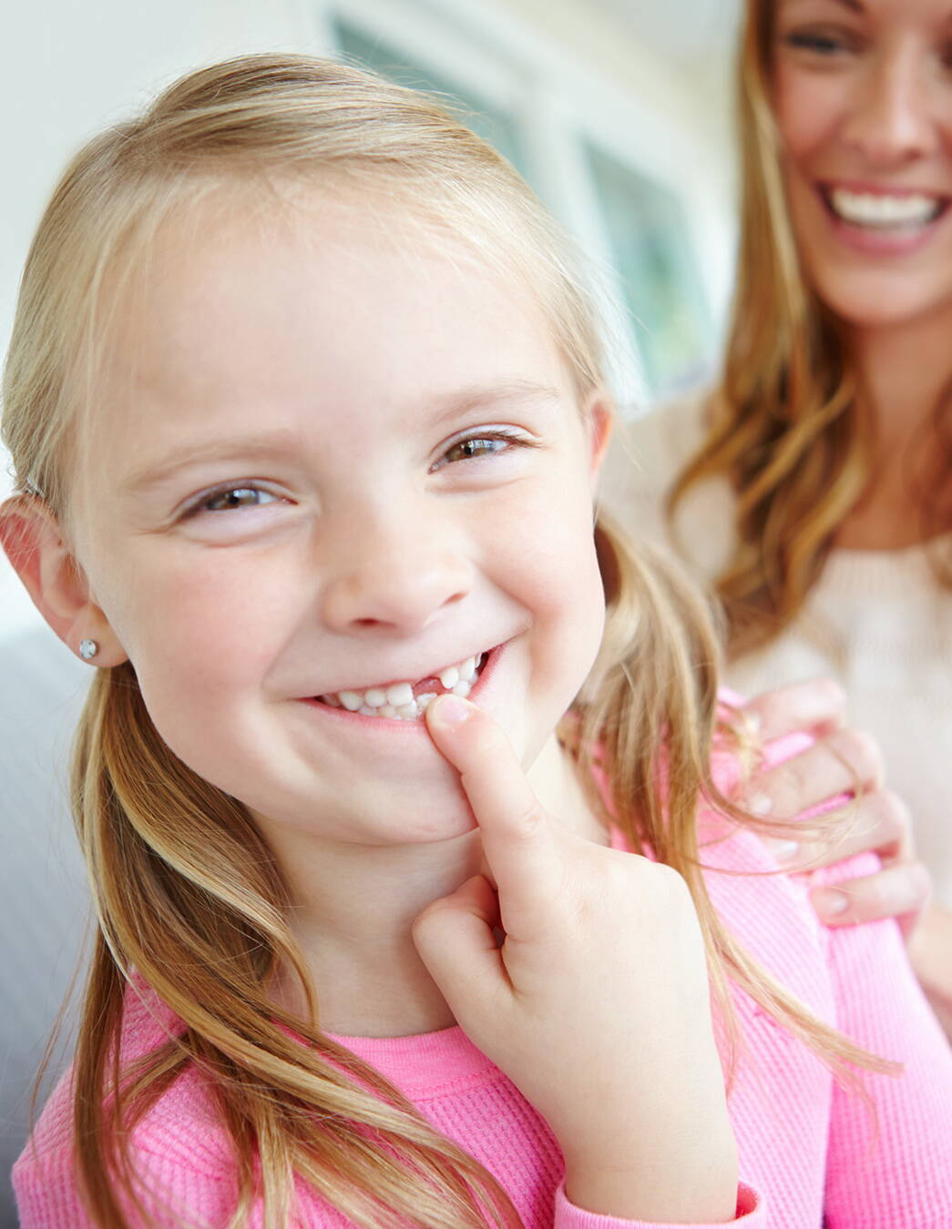 Una bambina svizzera di cinque anni mostra con orgoglio il suo spazio tra i denti. Questo momento ricorda ai genitori di pensare per tempo a un’assicurazione dentale adeguata.