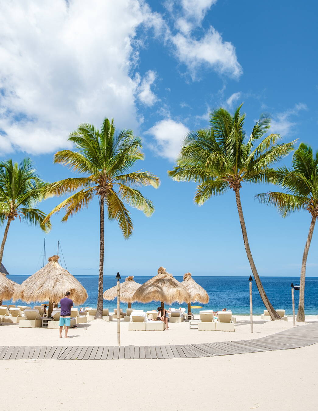 Ferienparadies mit Strand und Palmen Ein idyllisches Ferienressort mit Sandstrand, Palmen, Sonnenschirmen und Liegestühlen vor klarem Meer – perfekt für entspannte Auszeiten in der Schwangerschaft.