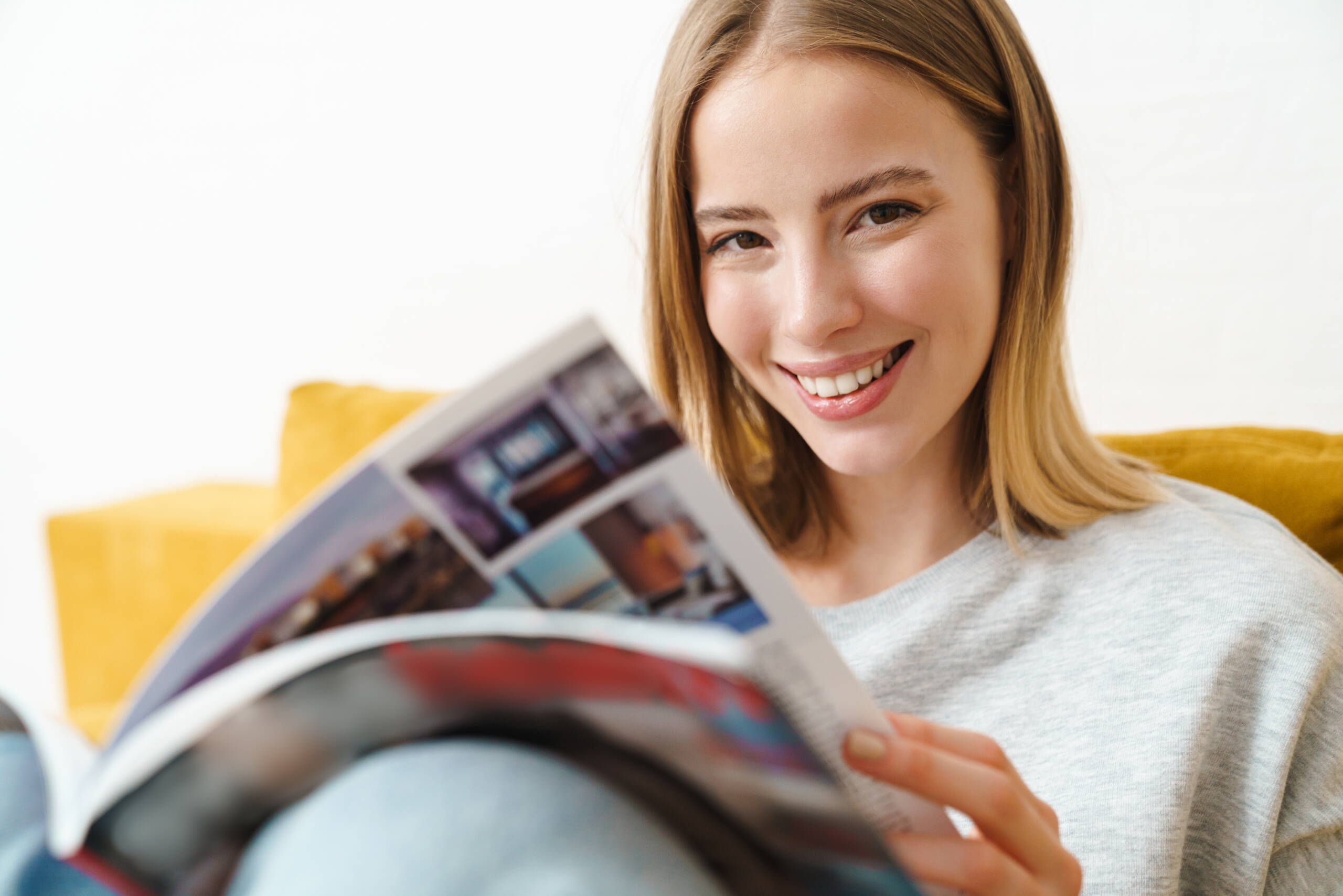 Une jeune femme feuillette un magazine avec intérêt – un moment d’inspiration et de compréhension de ce qui fait PRO LIFE.