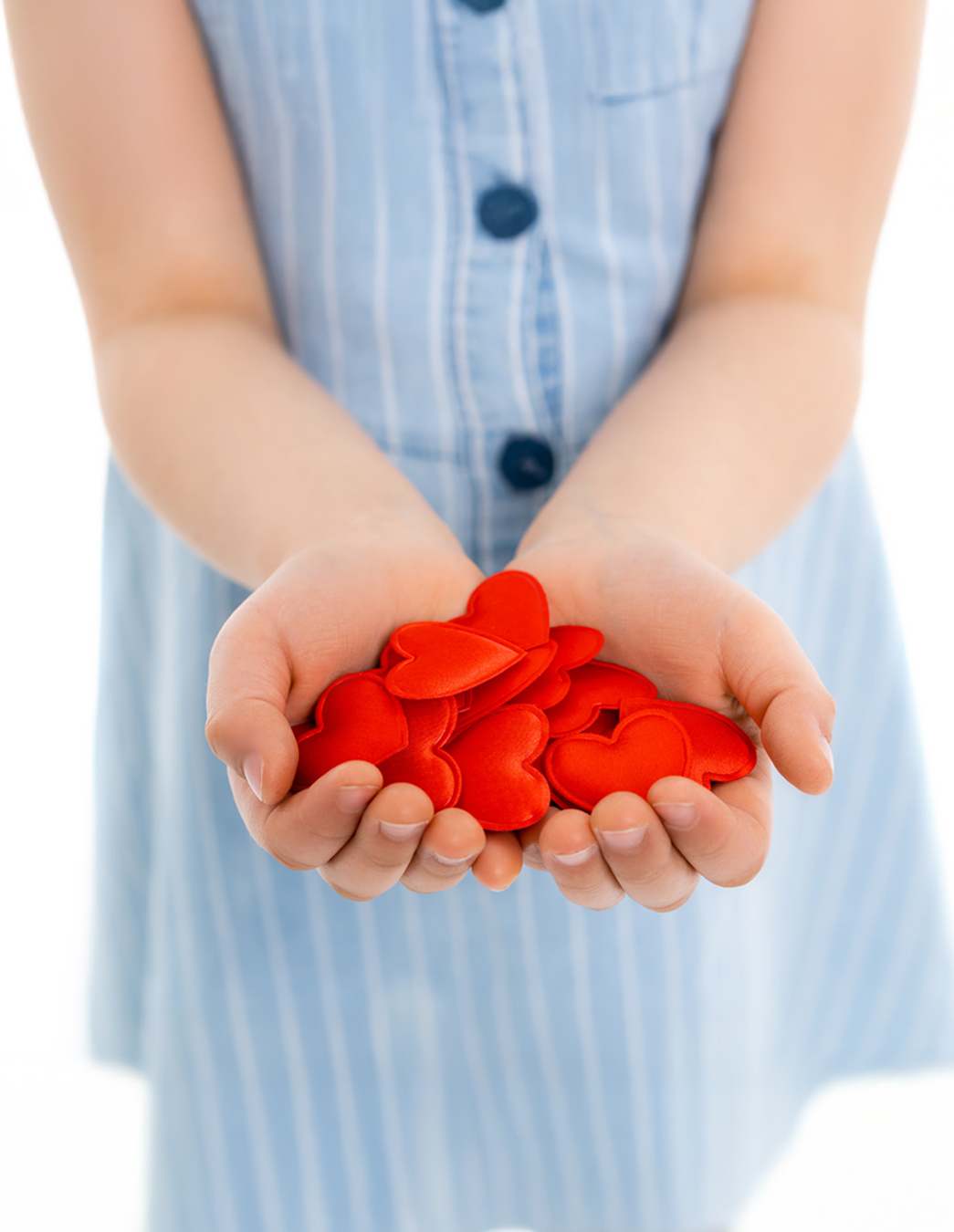 Une petite fille tient ses mains ouvertes – remplies de cœurs rouges. Une image émotive de bienveillance, de confiance et de soutien mutuel.