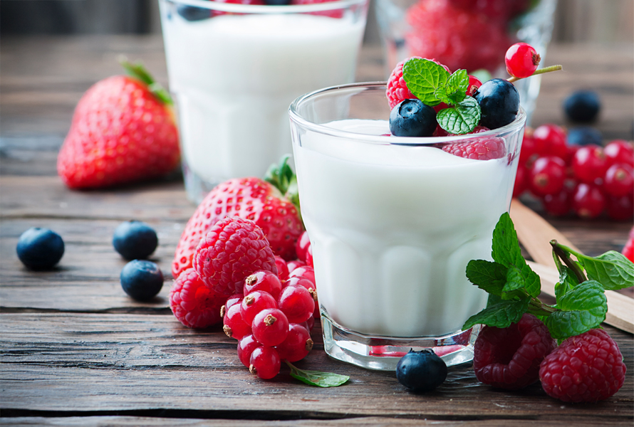 Eiweiss-Snack mit Farbkick – Joghurt mit Beeren Ein dekorativ geschichtetes Glas mit cremigem Naturjoghurt, frischen Beeren und Fruchtscheiben. Neben dem Glas liegen ein paar der verwendeten Früchte. Leicht, sättigend und ideal gegen Heisshunger.