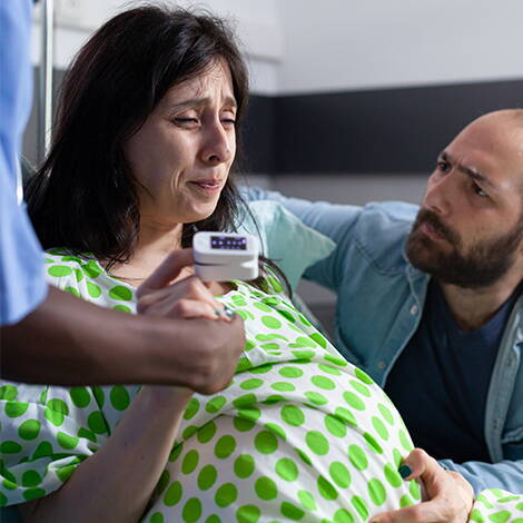 Wenn die Wehen beginnen Eine Frau in den Wehen stützt sich ab, ihr Partner kniet neben ihr und gibt ihr Halt – ein emotionaler Moment kurz vor der Geburt.