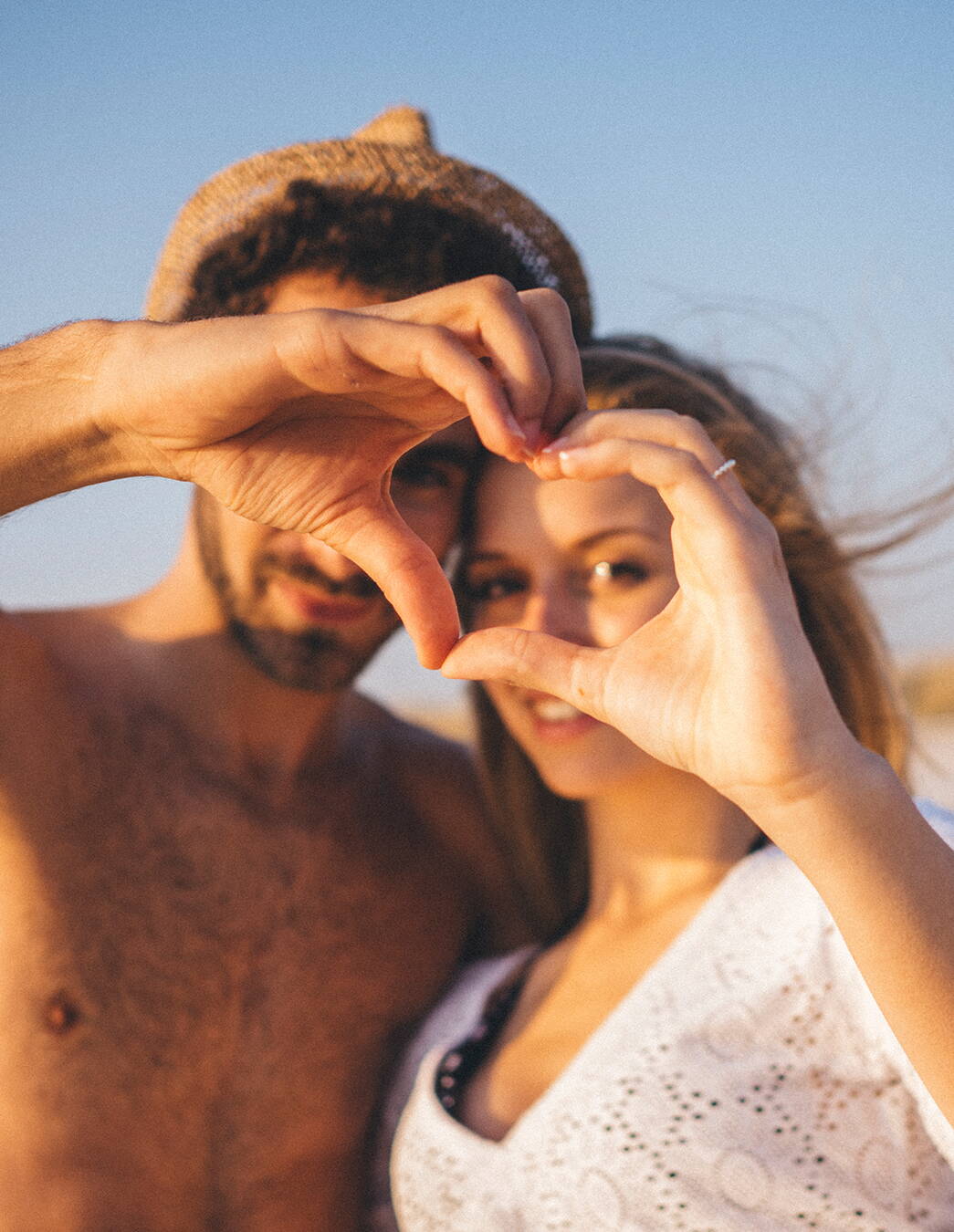 Gemeinsam stark – Zweisamkeit in der Schwangerschaft Glückliches Paar im Sonnenschein formt mit den Fingern ein Herz – ein Symbol für Zusammenhalt und Nähe in dieser besonderen Zeit.