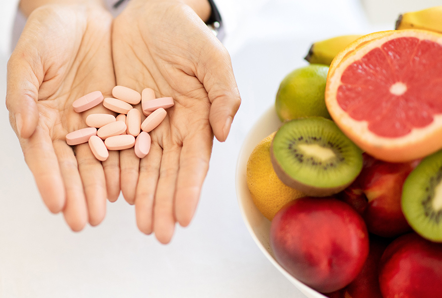 Eine Handvoll Vitamine Eine Frau hält Tabletten in den Händen – daneben frisches Obst: Symbol für die Bedeutung von Folsäure und Nährstoffen in der Frühschwangerschaft.