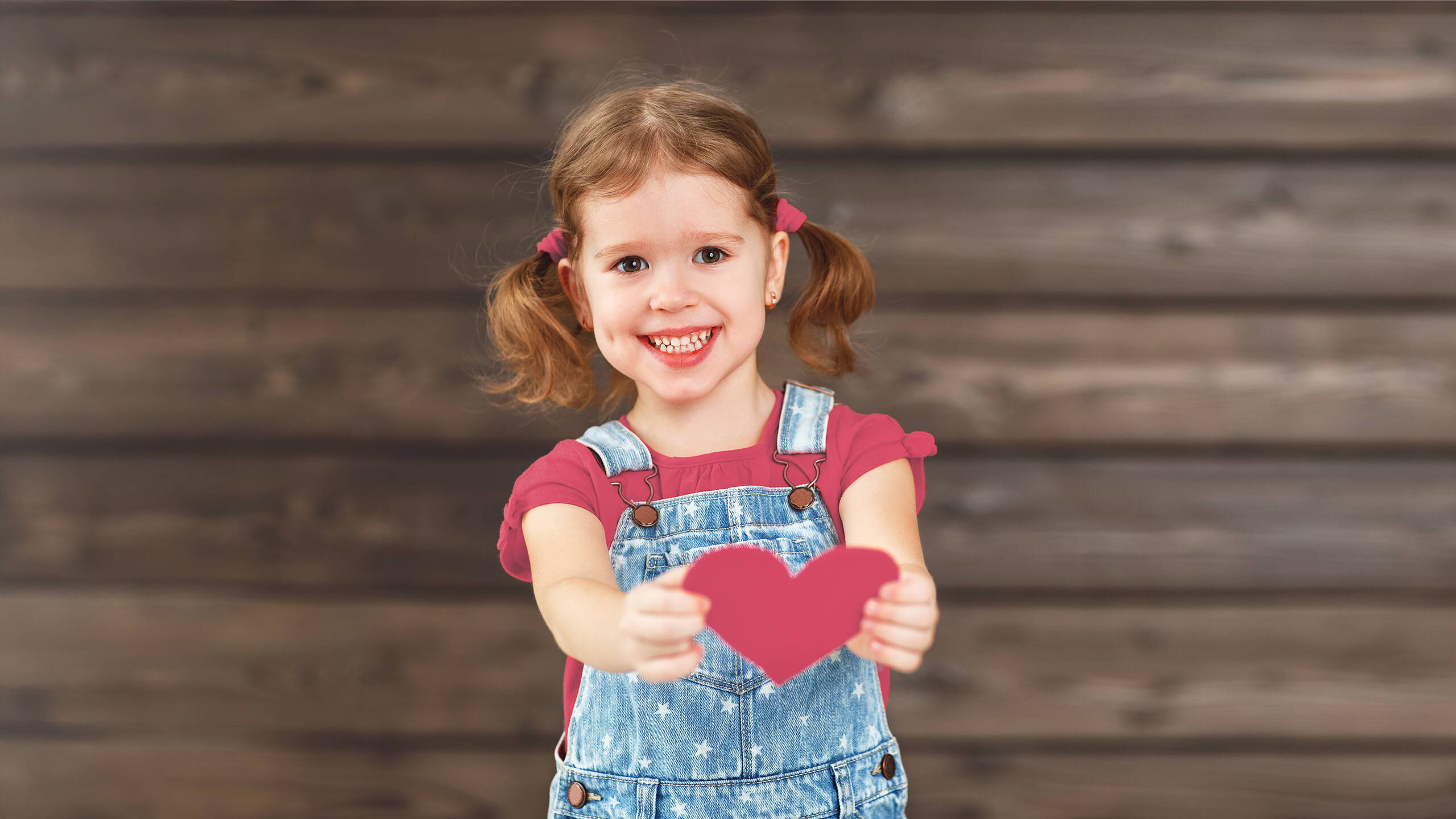 Une petite fille tend un cœur vers la caméra – un symbole fort de compassion et de vraie solidarité.