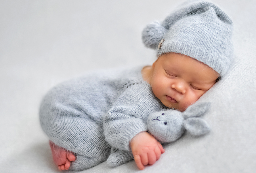 Neugeborenes mit gestricktem Hasen Schlafendes Baby kuschelt mit einem handgestrickten Hasen – Symbol für Geborgenheit und den neuen Lebensabschnitt.