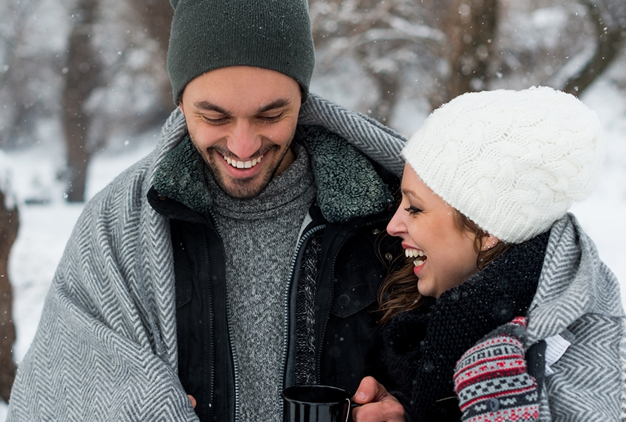 Junges Paar beim Winterspaziergang Ein Paar trinkt gemeinsam heissen Tee beim Spaziergang – Bewegung an der frischen Luft tut in der Schwangerschaft besonders gut.