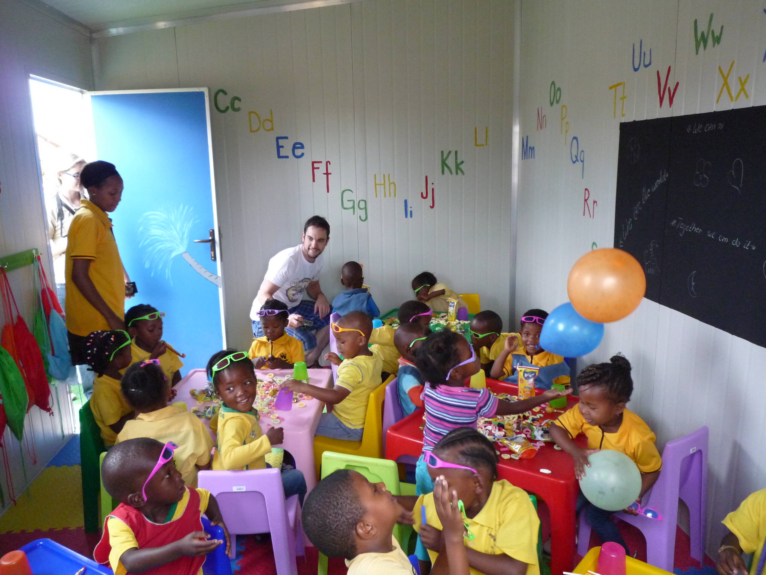 Lernen mit Freude Bei der Einweihung feiern Kinder mit einem Teammitglied im Unterrichtsraum. Kleine Überraschungen wie Süssigkeiten sorgen für strahlende Gesichter.
